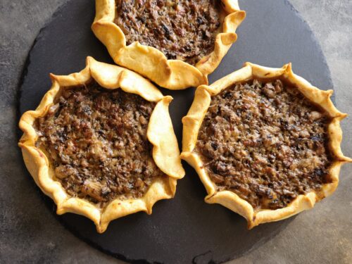 Rustic mini mushroom galettes with crispy crust and aromatic mushroom filling garnished with fresh herbs