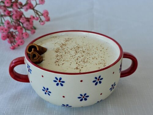 Bowl of creamy rice pudding garnished with cinnamon and raisins