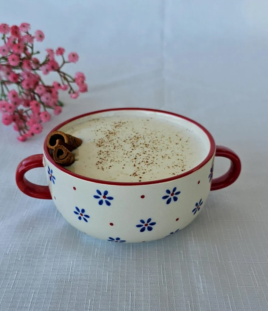 Bowl of creamy rice pudding garnished with cinnamon and raisins