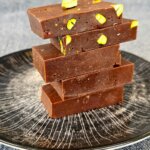 Home-made chocolate with nuts and pistachios served on a wooden tray with a luxurious and rustic presentation.