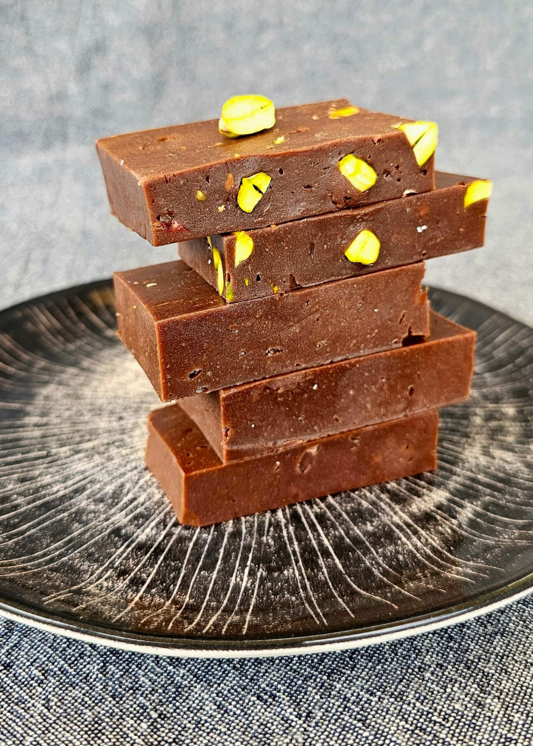 Home-made chocolate with nuts and pistachios served on a wooden tray with a luxurious and rustic presentation.