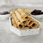 Thin golden crepes stacked with fresh fruit toppings and a drizzle of chocolate.