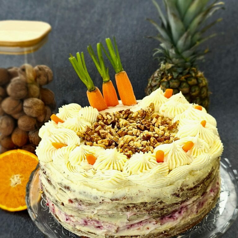 Moist Carrot Cake with cream cheese frosting and raspberry jam garnished with fresh carrots and nuts