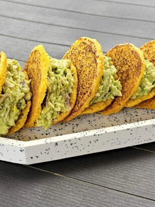 Gorditas with chicken and avocado on a plate, garnished with fresh herbs and served with sauces.