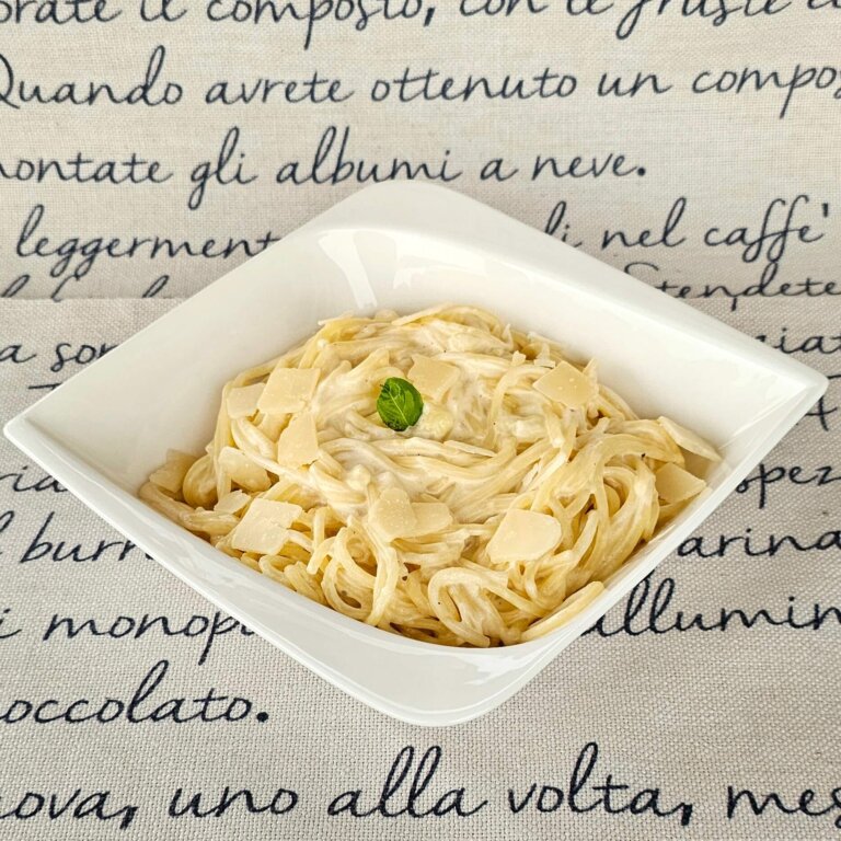 A plate of Quattro Formaggi Pasta garnished with parsley and freshly grated parmesan.