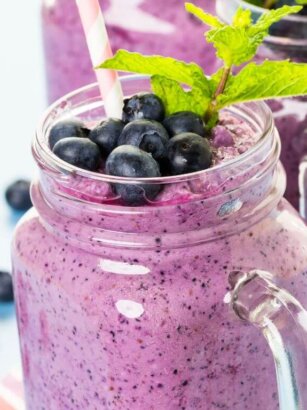 Smoothie ingredients including frozen blueberries, clementine, banana, and yogurt on a counter