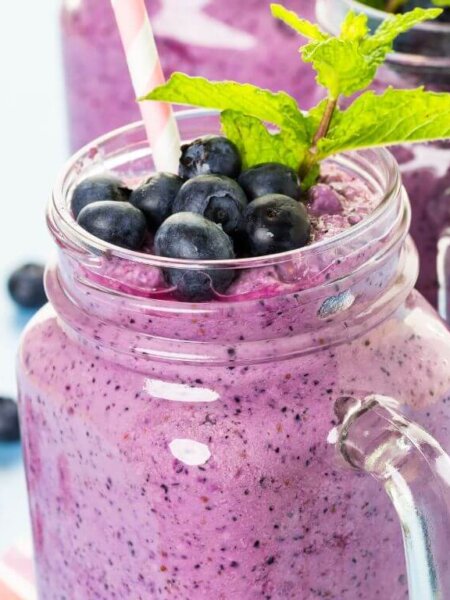 Smoothie ingredients including frozen blueberries, clementine, banana, and yogurt on a counter