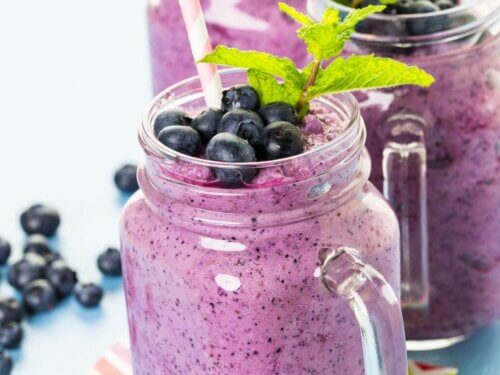 Smoothie ingredients including frozen blueberries, clementine, banana, and yogurt on a counter