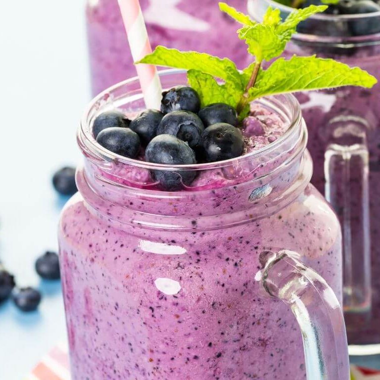 Smoothie ingredients including frozen blueberries, clementine, banana, and yogurt on a counter