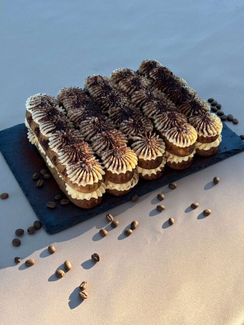 Tiramisu dessert with layers of coffee-soaked ladyfingers, mascarpone, and cocoa, served on a white plate.