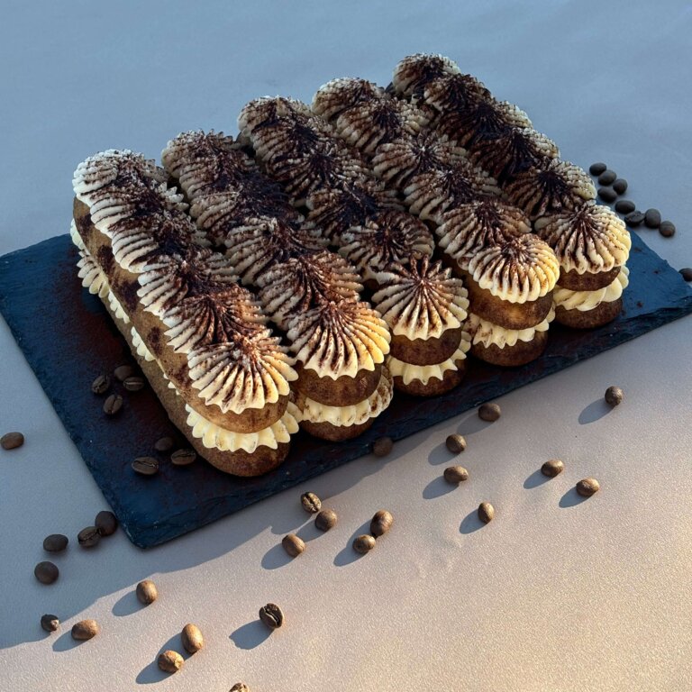 Tiramisu dessert with layers of coffee-soaked ladyfingers, mascarpone, and cocoa, served on a white plate.
